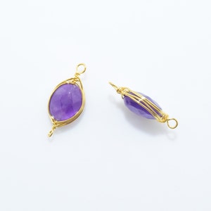 K&ouml;nnte beinhalten: Zwei golddrahtgewickelte Amethyst-Anh&auml;nger. Die Edelsteine sind oval geformt und haben einen violetten Farbton. Der Draht ist um die Edelsteine gewickelt, um ein filigranes und komplexes Design zu schaffen.