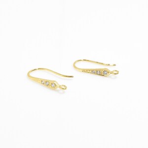 May include: A pair of gold-tone earring hooks with clear crystal accents.