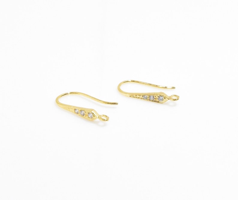 May include: A pair of gold-tone earring hooks with clear crystal accents.