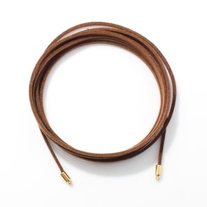 May include: A brown leather cord with gold metal end caps.