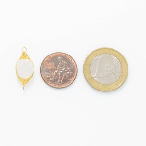 Pu&ograve; includere: Un ciondolo avvolto in filo d'oro con una pietra ovale bianca. Il ciondolo &egrave; mostrato accanto a un penny americano e una moneta da un euro per il confronto delle dimensioni.