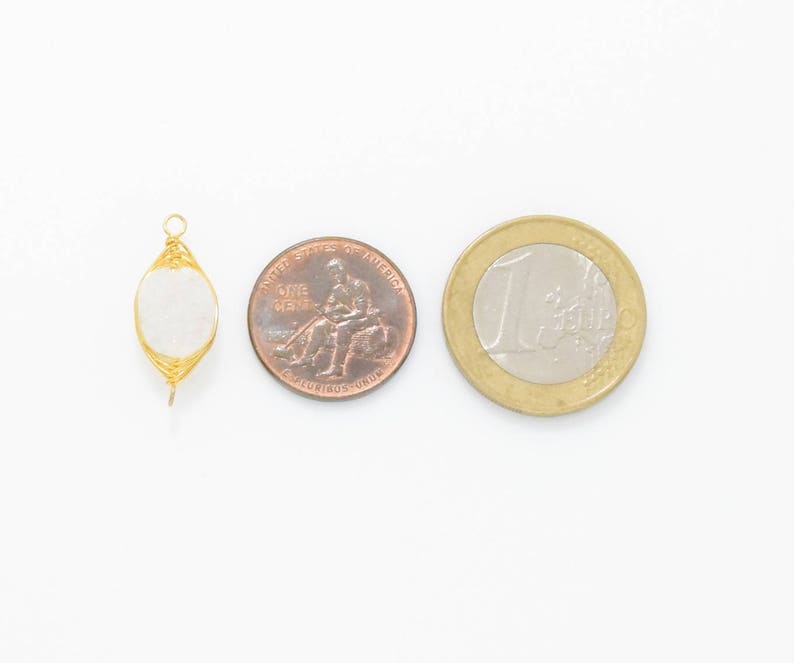 Pu&ograve; includere: Un ciondolo avvolto in filo d'oro con una pietra ovale bianca. Il ciondolo &egrave; mostrato accanto a un penny americano e una moneta da un euro per il confronto delle dimensioni.