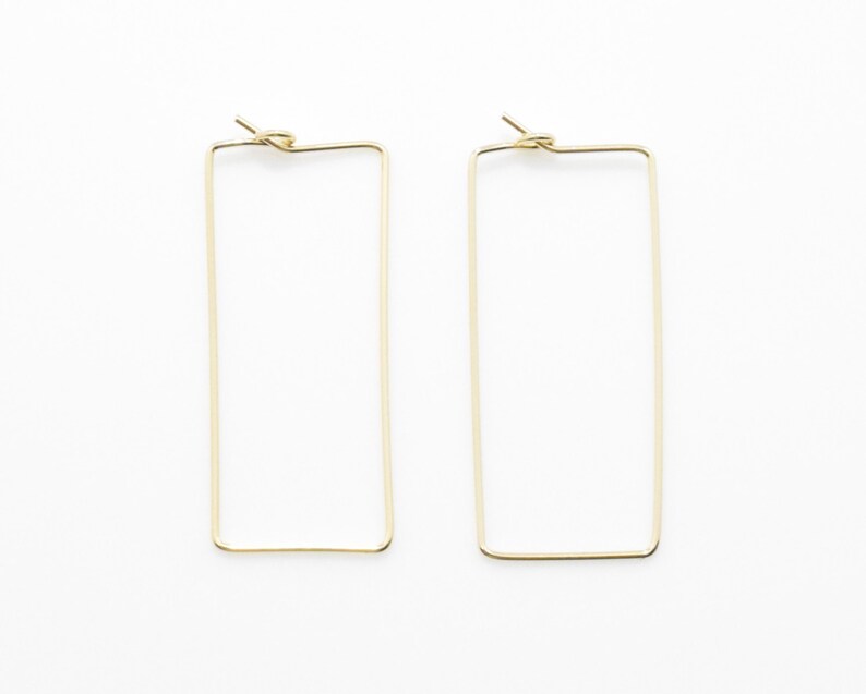 May include: A pair of gold rectangle hoop earrings. The earrings are simple and minimalist.