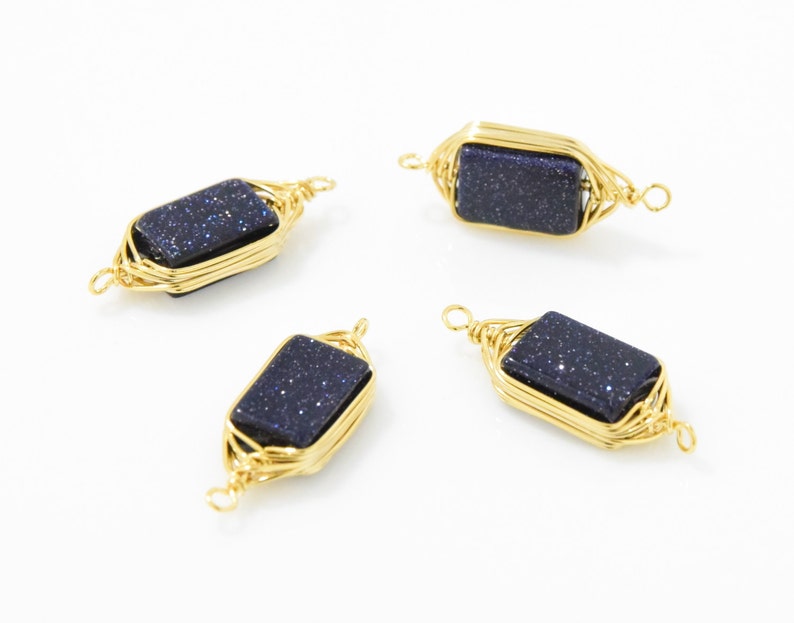 May include: Four gold-colored wire-wrapped pendants. Each pendant features a rectangular, dark blue stone with sparkling inclusions. The wire is intricately woven around the stone, creating a decorative frame with loops at each end.