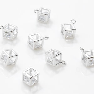 Könnte beinhalten: Acht silberne Würfel-Anhänger mit klaren Kristall-Akzenten. Jeder Anhänger hat eine kleine Schlaufe zum Anbringen an Schmuck.