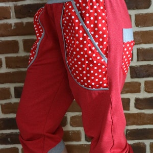 May include: Red capri pants with white polka dots and gray trim. The pants have a unique design with a large pocket on the side.