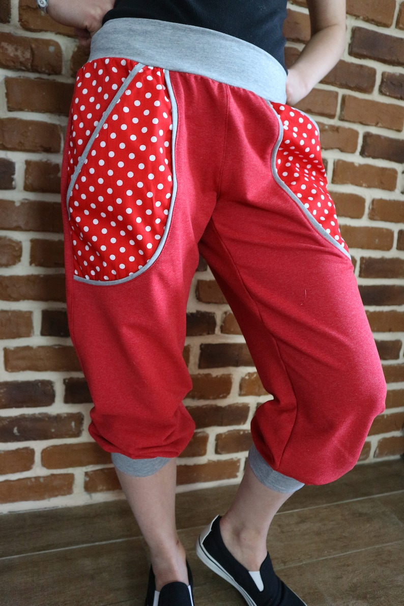 May include: Red sweatpants with grey waistband and cuffs. The sweatpants have large pockets on the sides with white polka dots on a red background.
