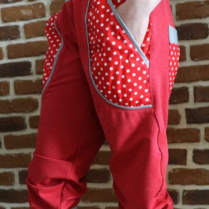 May include: Red capri pants with a white polka dot fabric detail on the side pockets. The pants have a gray waistband and cuffs.