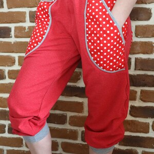 May include: Red capri pants with white polka dot fabric accents on the pockets. The pants have a gray waistband and gray trim at the bottom of the legs.
