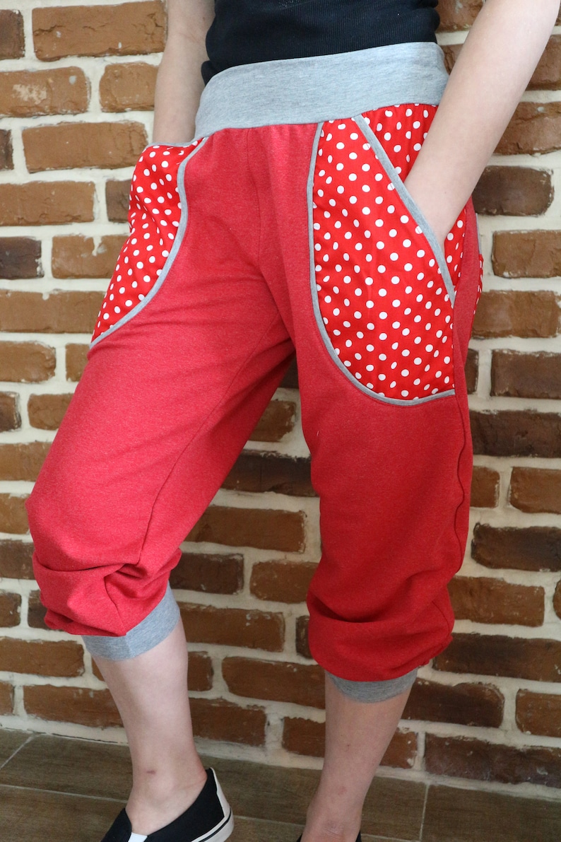 May include: Red capri pants with white polka dot fabric accents on the pockets. The pants have a gray waistband and gray trim at the bottom of the legs.