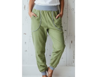 May include: Green corduroy pants with a gray waistband and cuffs. The pants have two front pockets with a curved design and a relaxed fit. The fabric has a vertical ribbed texture.