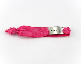 May include: A pink elastic bracelet with a silver charm that says "nena".