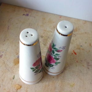 A pair of tall ceramic salt and pepper shakers with gold trim and rose transfers.
