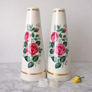 A pair of tall ceramic salt and pepper shakers with gold trim and rose transfers.