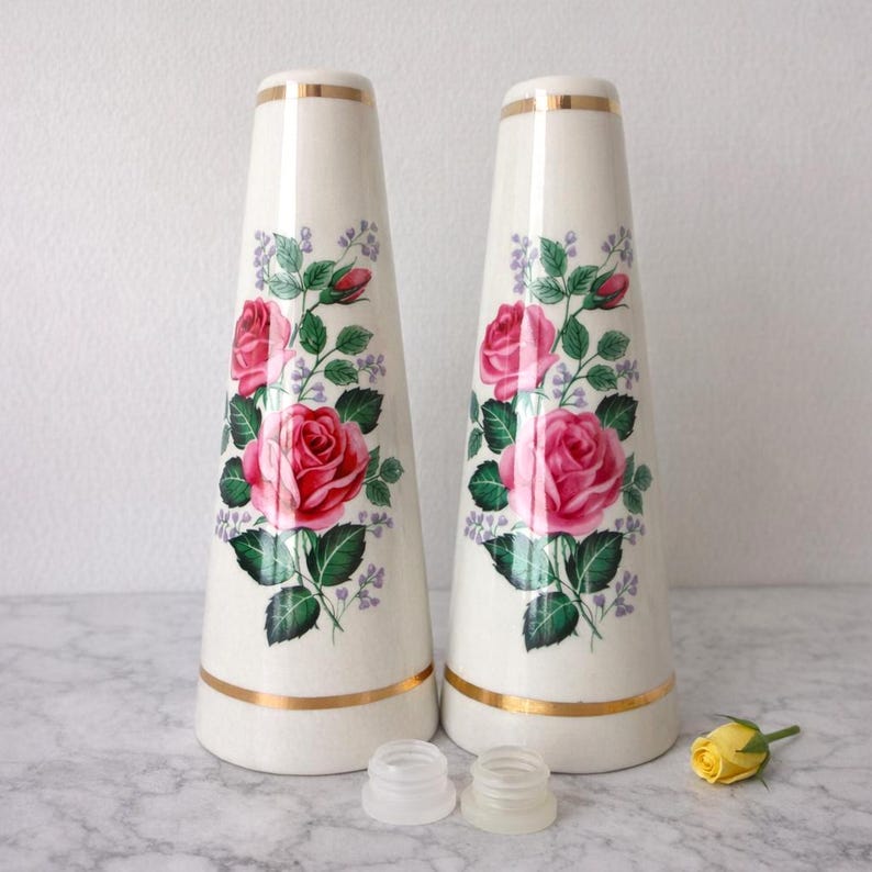 A pair of tall ceramic salt and pepper shakers with gold trim and rose transfers.