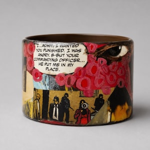 Handmade Comic Book Pop Art bangle with a glossy upcycled wood cuff, featuring a vintage comic collage of pink and red graphics, a large eye, illustrated characters, flames and a speech bubble reading “I...ADMIT, I WANTED YOU