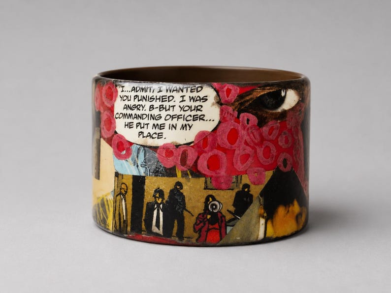 Handmade Comic Book Pop Art bangle with a glossy upcycled wood cuff, featuring a vintage comic collage of pink and red graphics, a large eye, illustrated characters, flames and a speech bubble reading “I...ADMIT, I WANTED YOU