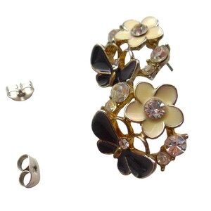 Close-up of vintage butterfly earrings featuring black white enamel wings and cz stud earrings set in gold plated studs. The enamel earrings have a cluster studs design with sculptural studs detailing, ideal for fans of retro earrings and statement studs. Lightweight and elegant, these dainty earrings are nature inspired, part of a slow fashion collection of handmade jewelry crafted for archival charm.