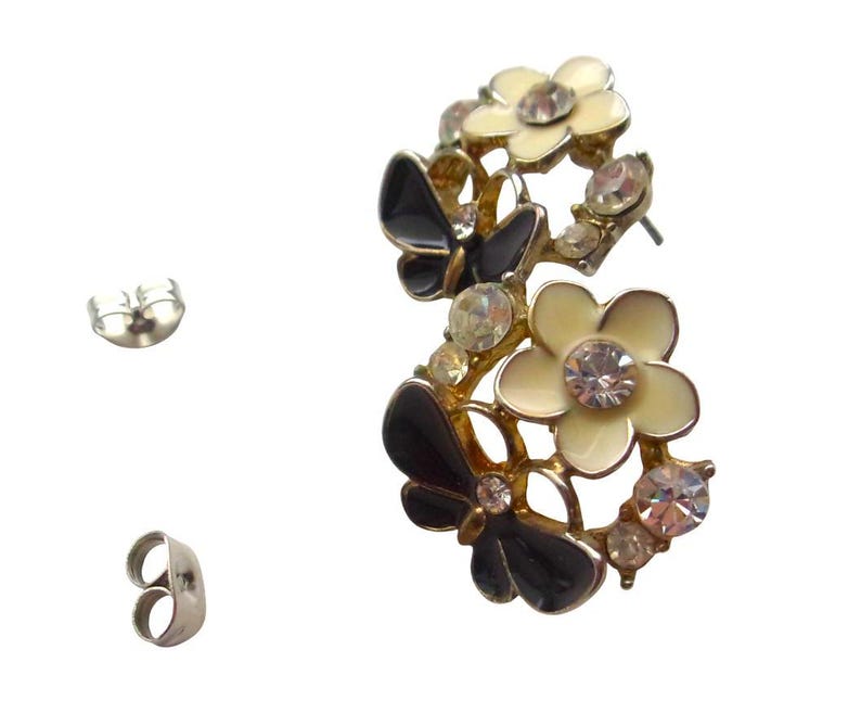 Close-up of vintage butterfly earrings featuring black white enamel wings and cz stud earrings set in gold plated studs. The enamel earrings have a cluster studs design with sculptural studs detailing, ideal for fans of retro earrings and statement studs. Lightweight and elegant, these dainty earrings are nature inspired, part of a slow fashion collection of handmade jewelry crafted for archival charm.