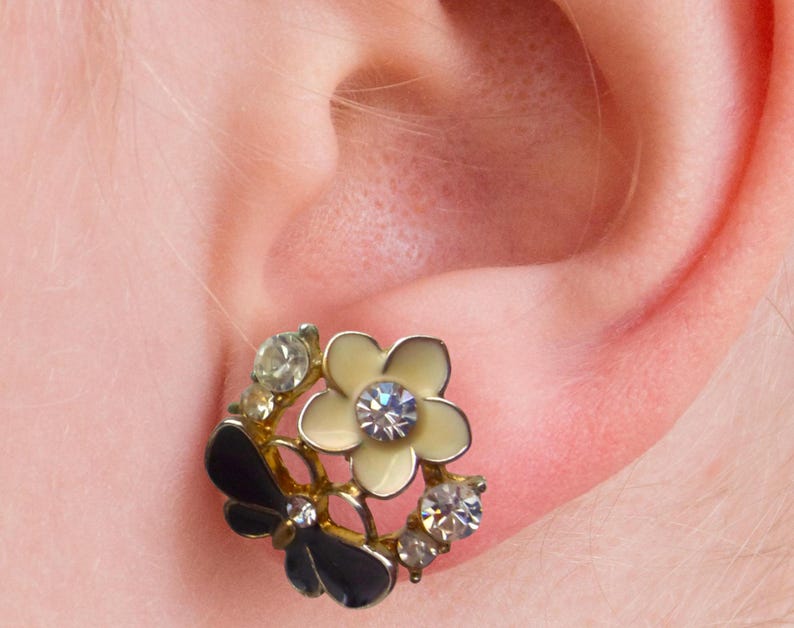 Close-up of vintage butterfly earrings featuring black white enamel wings and cz stud earrings set in gold plated studs. The enamel earrings have a cluster studs design with sculptural studs detailing, ideal for fans of retro earrings and statement studs. Lightweight and elegant, these dainty earrings are nature inspired, part of a slow fashion collection of handmade jewelry crafted for archival charm.