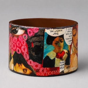 Handmade upcycled wood comic book bangle featuring a colourful Pop Art collage with speech bubbles, illustrated characters and bold red, black and turquoise details. Visible text includes “THAT WASN’T ME” and “USA TODAY.”