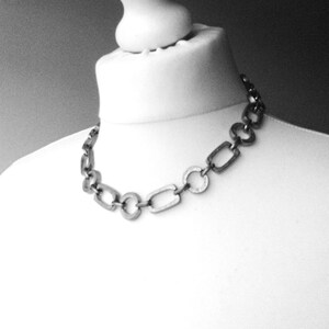 Close-up of a Brutalist Necklace featuring a Steel Link Chain and Geometric Choker design. This Industrial Style piece showcases Sculptural Steel with a bold Architectural Look, ideal for Urban Jewelry UK collectors. A Statement Chain and Unisex Necklace, it’s a Sustainable Gift and perfect Gift for Him. Inspired by MCM Revival, this Bold Steel Piece blends raw texture with timeless edge.
