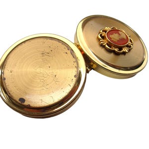 A small vintage pillbox with a red-and-ivory cameo trinket framed in gold filigree, this gold keepsake doubles as a mini treasure and handmade box. Styled as a regency charm, it’s perfect for gifting as a victorian gift or historical gift. The aged finish enhances its appeal as an antique case, ideal for retro cottage collectors seeking micro luxury and collectible art in a timeless rose gold box.