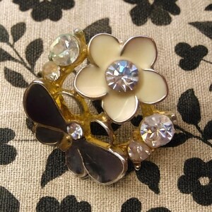 Close-up of vintage butterfly earrings featuring black white enamel wings and cz stud earrings set in gold plated studs. The enamel earrings have a cluster studs design with sculptural studs detailing, ideal for fans of retro earrings and statement studs. Lightweight and elegant, these dainty earrings are nature inspired, part of a slow fashion collection of handmade jewelry crafted for archival charm.