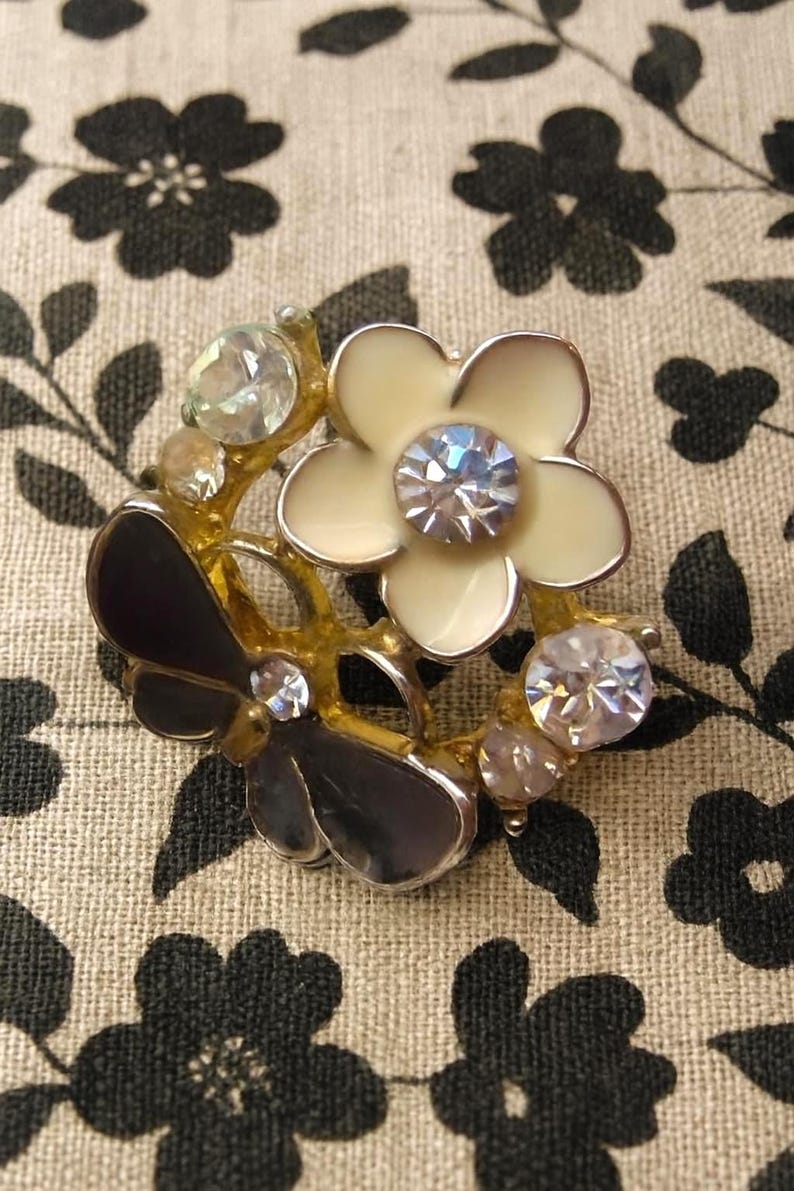 Close-up of vintage butterfly earrings featuring black white enamel wings and cz stud earrings set in gold plated studs. The enamel earrings have a cluster studs design with sculptural studs detailing, ideal for fans of retro earrings and statement studs. Lightweight and elegant, these dainty earrings are nature inspired, part of a slow fashion collection of handmade jewelry crafted for archival charm.
