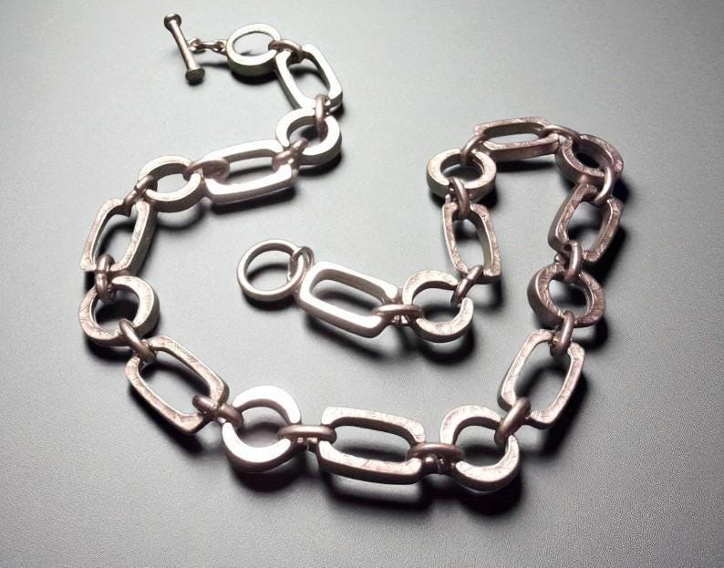 Close-up of a Brutalist Necklace featuring a Steel Link Chain and Geometric Choker design. This Industrial Style piece showcases Sculptural Steel with a bold Architectural Look, ideal for Urban Jewelry UK collectors. A Statement Chain and Unisex Necklace, it’s a Sustainable Gift and perfect Gift for Him. Inspired by MCM Revival, this Bold Steel Piece blends raw texture with timeless edge.