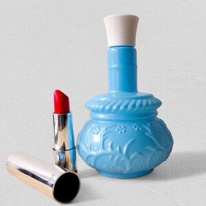 A rare Avon Perfume Bottle in sculpted Milk Glass Vase form, perfect for Vintage Vanity styling. This Floral Glassware piece adds Retro Bottle Decor charm to any space. Featuring Blue White Decor tones, it’s a thoughtful Sustainable Gift and elegant Collectible Glass accent. Ideal for Eco Home Decor, this 5.5" Vanity Bottle makes a nostalgic Gift for Her. A true Repurposed Decor treasure in classic Midcentury Style.