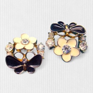 Close-up of vintage butterfly earrings featuring black white enamel wings and cz stud earrings set in gold plated studs. The enamel earrings have a cluster studs design with sculptural studs detailing, ideal for fans of retro earrings and statement studs. Lightweight and elegant, these dainty earrings are nature inspired, part of a slow fashion collection of handmade jewelry crafted for archival charm.