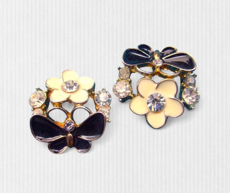 Close-up of vintage butterfly earrings featuring black white enamel wings and cz stud earrings set in gold plated studs. The enamel earrings have a cluster studs design with sculptural studs detailing, ideal for fans of retro earrings and statement studs. Lightweight and elegant, these dainty earrings are nature inspired, part of a slow fashion collection of handmade jewelry crafted for archival charm.