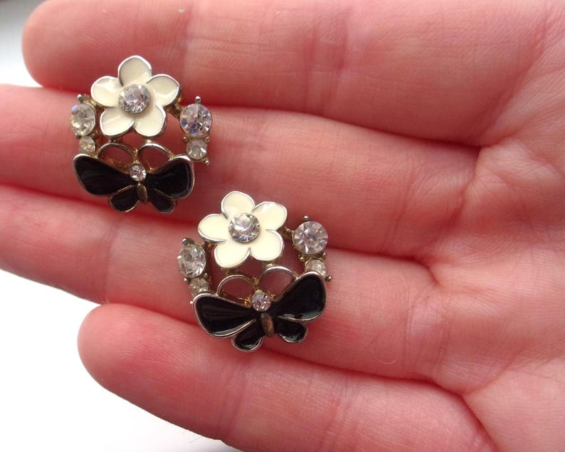 Close-up of vintage butterfly earrings featuring black white enamel wings and cz stud earrings set in gold plated studs. The enamel earrings have a cluster studs design with sculptural studs detailing, ideal for fans of retro earrings and statement studs. Lightweight and elegant, these dainty earrings are nature inspired, part of a slow fashion collection of handmade jewelry crafted for archival charm.