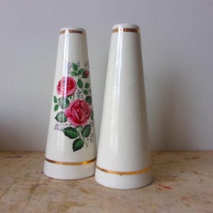 A pair of tall ceramic salt and pepper shakers with gold trim and rose transfers.