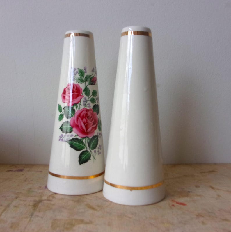 A pair of tall ceramic salt and pepper shakers with gold trim and rose transfers.