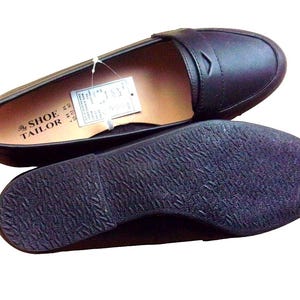 A pair of Vintage Loafers styled as Black Leather Loafers with a bow detail, these 1980s Leather Flats are timeless Bow Detail Loafers made from Soft Leather Shoes. Perfect as Retro Work Shoes, Minimalist Loafers, or Office Leather Flats, they channel Preppy Style Shoes and Quiet Luxury. Designed as Gender Neutral Shoes, they reflect Archive Fashion values and sustainable elegance in classic Leather Slip Ons.