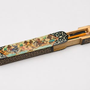 Handcrafted Persian miniature desk box with sliding compartment holding a pen and pencil, photographed in a light grey studio to highlight its vintage marquetry craftsmanship.