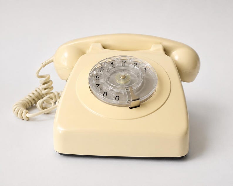 A front view of a cream-colored rotary dial telephone with the handset receiver resting on its cradle against a white background.