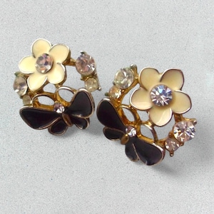 Close-up of vintage butterfly earrings featuring black white enamel wings and cz stud earrings set in gold plated studs. The enamel earrings have a cluster studs design with sculptural studs detailing, ideal for fans of retro earrings and statement studs. Lightweight and elegant, these dainty earrings are nature inspired, part of a slow fashion collection of handmade jewelry crafted for archival charm.