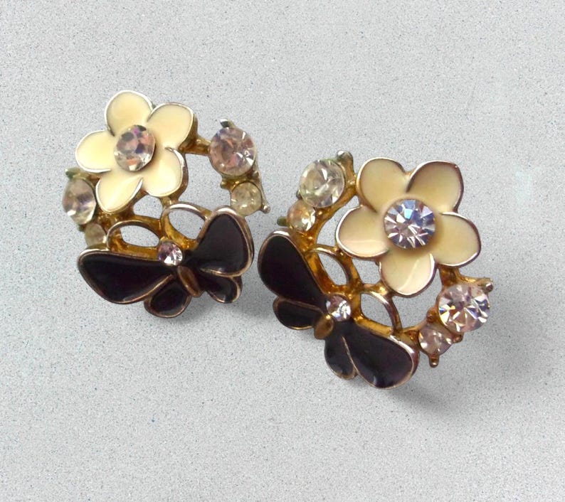 Close-up of vintage butterfly earrings featuring black white enamel wings and cz stud earrings set in gold plated studs. The enamel earrings have a cluster studs design with sculptural studs detailing, ideal for fans of retro earrings and statement studs. Lightweight and elegant, these dainty earrings are nature inspired, part of a slow fashion collection of handmade jewelry crafted for archival charm.