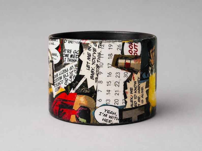 Handmade upcycled wood Comic Book bangle featuring a dramatic Pop Art collage with a large eye, pink circular graphics, illustrated figures and flames. Speech bubble reads “I...ADMIT, I WANTED YOU PUNISHED. I WAS ANGRY. B-BUT YOUR COMMANDING OFFICER... HE PUT ME IN MY PLACE.”