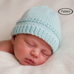Könnte beinhalten: Hellblaue gestrickte Baby-Mütze mit dekorativem Rand. Die Mütze ist aus weichem Garn gefertigt und für Neugeborene konzipiert. Das Wort "Pattern" befindet sich in einer schwarzen ovalen Form in der oberen rechten Ecke.