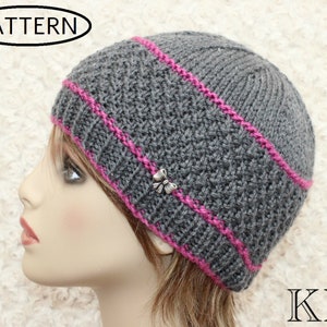 May include: Grey knitted beanie with a pink stripe around the brim and a silver butterfly charm. The beanie is worn by a mannequin.