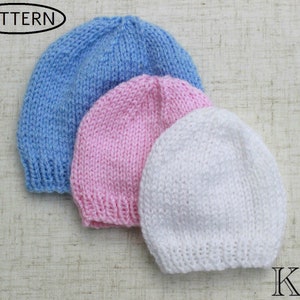 May include: Three knitted baby hats in blue, pink, and white. The hats are stacked on top of each other.