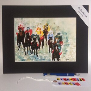 May include: A framed watercolor painting of a horse race. The horses are black and the riders are wearing colorful jockey silks. The painting is set against a white background with a light blue sky.