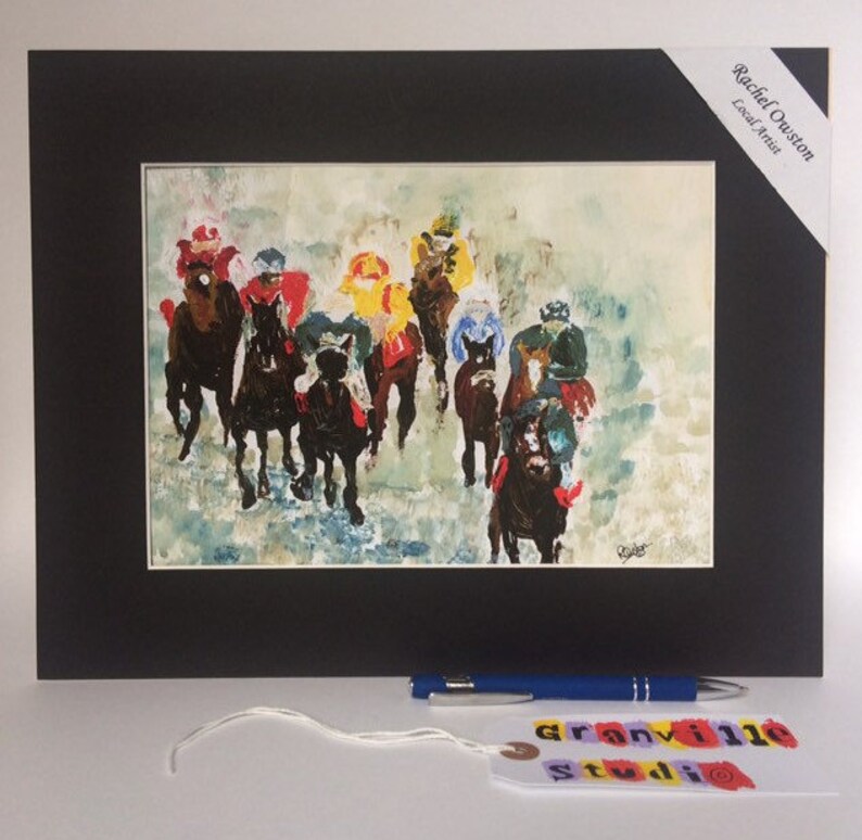 May include: A framed watercolor painting of a horse race. The horses are black and the riders are wearing colorful jockey silks. The painting is set against a white background with a light blue sky.
