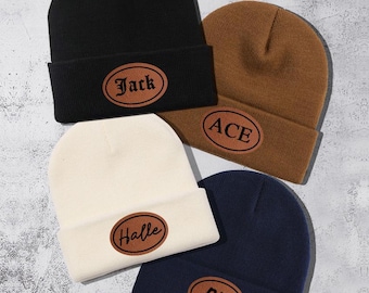 May include: Four knit beanies with different names on leather patches. The beanies are black, brown, white, and navy blue. The names on the patches are Jack, Ace, Halle, and Bill.