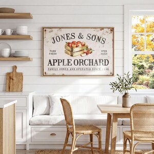 a cozy kitchen scene with a rustic wooden table and chairs, a framed sign for Jones & Sons Apple Orchard, and shelves displaying various kitchen items.