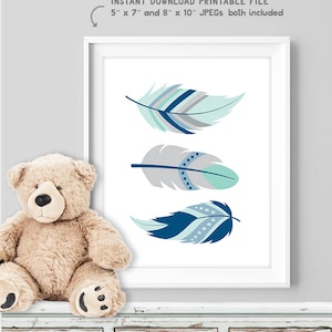 May include: A framed print with three decorative feathers in blue, teal, and grey. The white framed print includes the text "INSTANT DOWNLOAD PRINTABLE FILE 5" x 7" and 8" x 10" JPEGs both included". The print is suitable for a nursery.